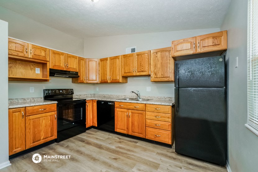 a kitchen with wooden cabinets and a black refrigerator