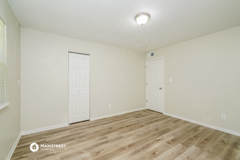 the spacious living room with white walls and wood flooring