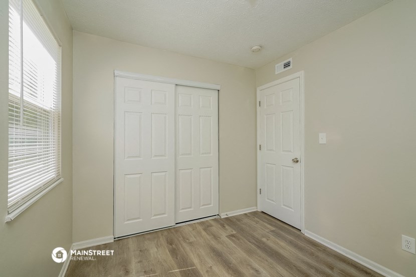 the living room of an apartment with two doors and a window