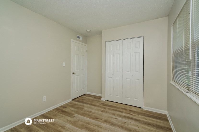 the spacious living room with two closets and a window