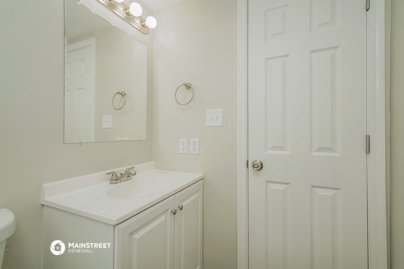 a bathroom with a sink and a mirror and a door