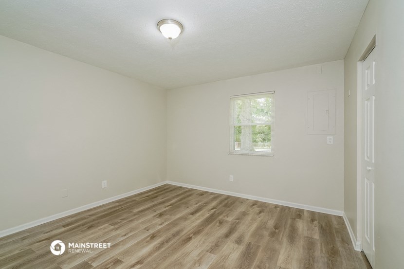 the spacious living room with wood flooring and a window