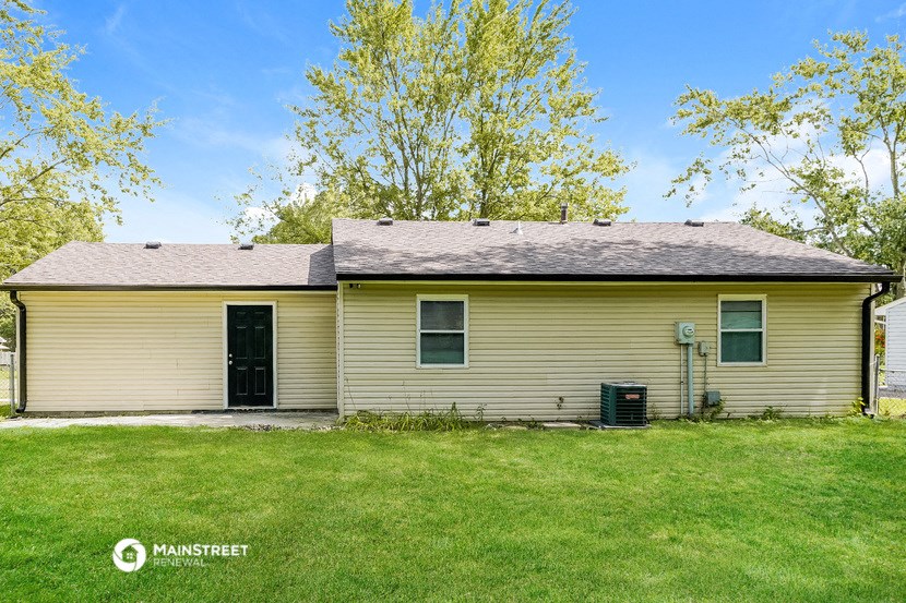 a yellow house with a grassy yard and a tree