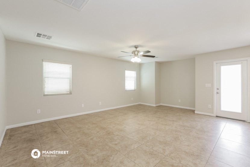 the spacious living room with tile flooring and a ceiling fan
