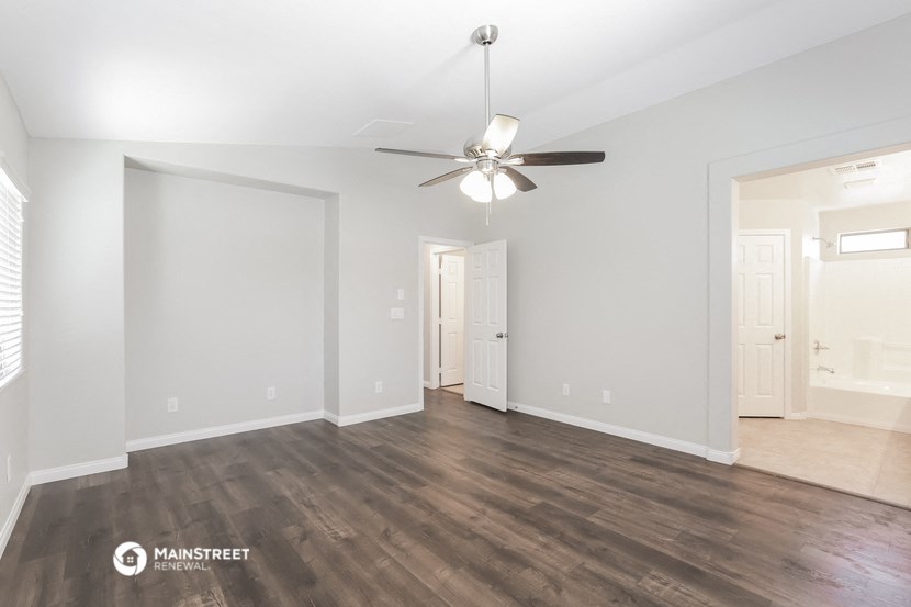 the spacious living room with wood flooring and a ceiling fan