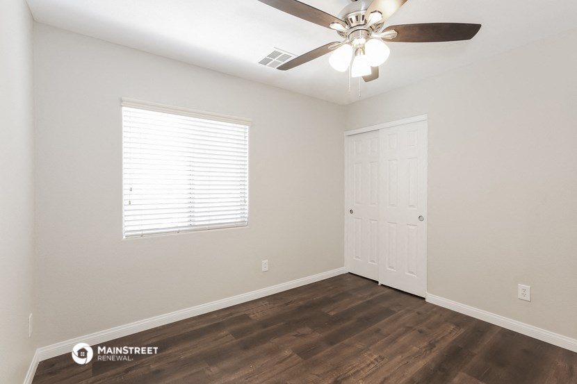 the spacious living room with a ceiling fan and a door to the bedroom