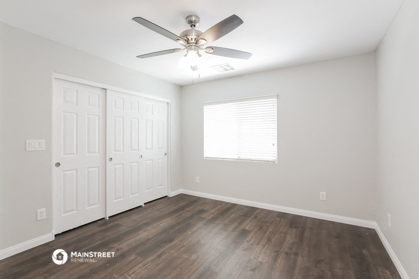 the spacious living room with a ceiling fan and a window