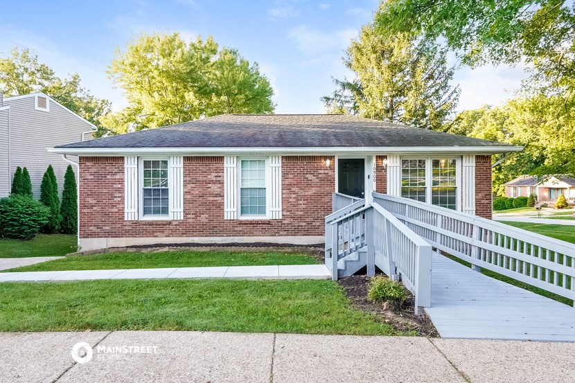 a small brick house with a porch and a white deck