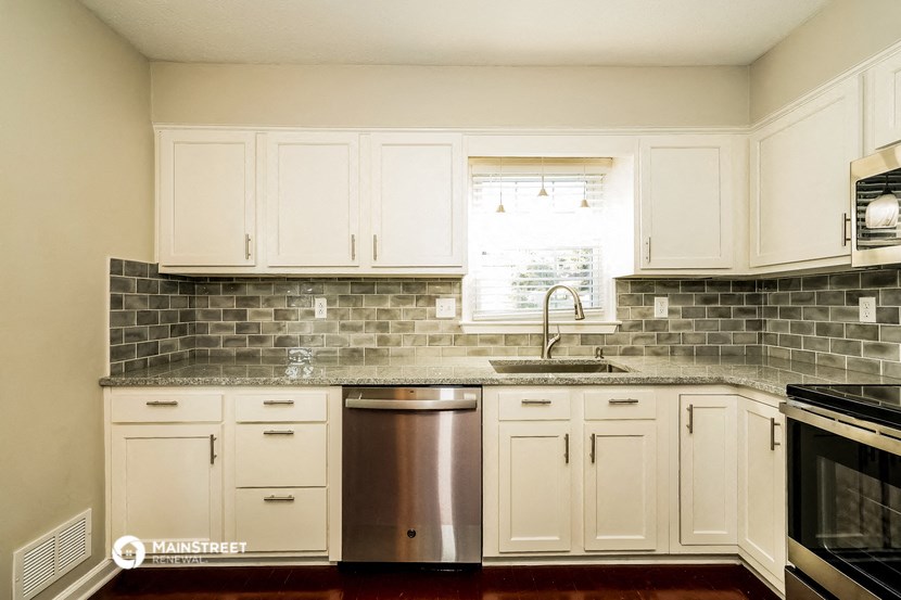 a kitchen with white cabinets and a sink and a window