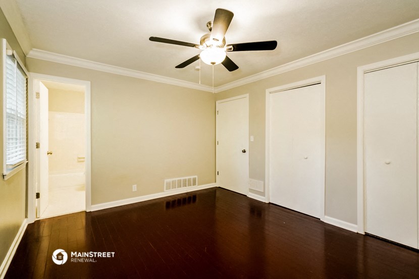 a empty living room with wood floors and a ceiling fan