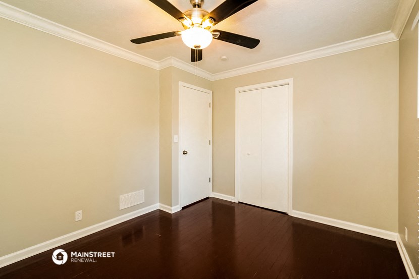 a empty room with wooden floors and a ceiling fan