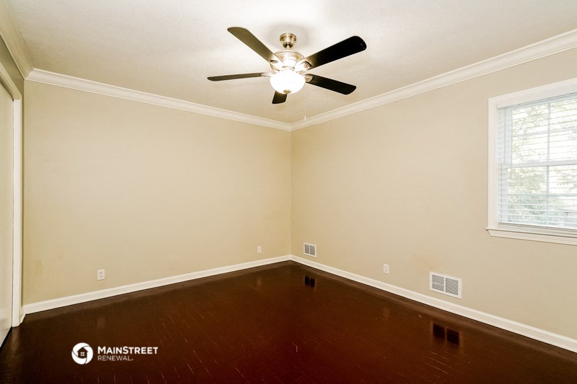 a empty room with wooden floors and a ceiling fan
