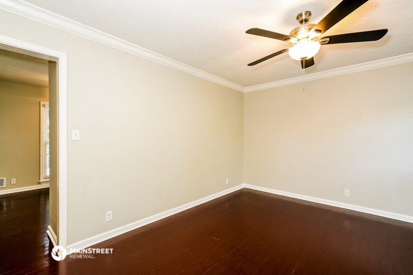 a empty room with a ceiling fan and wood floors