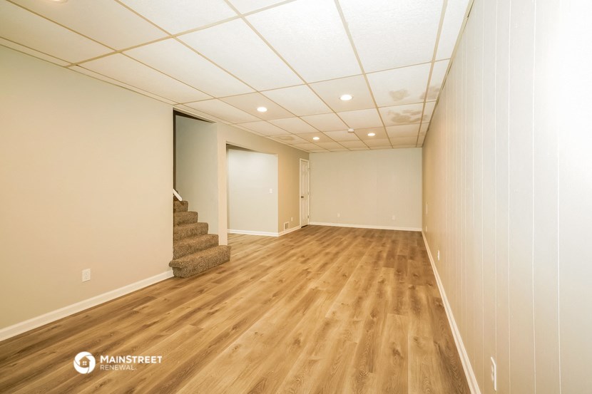 the living room and dining room of a house with wooden floors and white walls