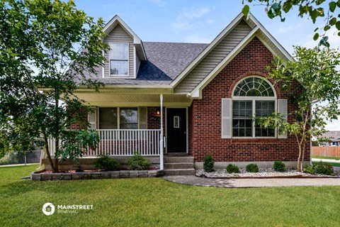 a red brick house with a porch and a lawn