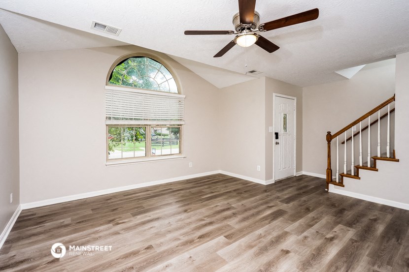 an empty living room with a ceiling fan and a window