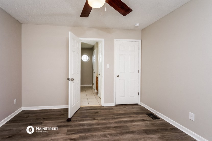 a living room with a ceiling fan and a door to a hallway