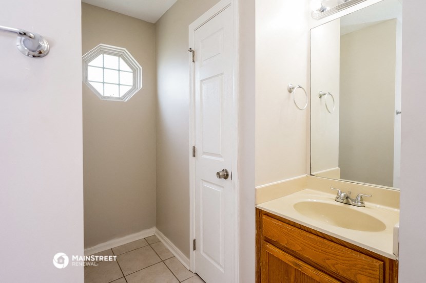 a bathroom with a white door and a sink and a mirror