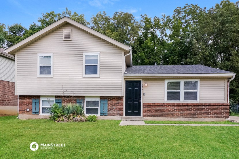 a white house with a black door and a green lawn