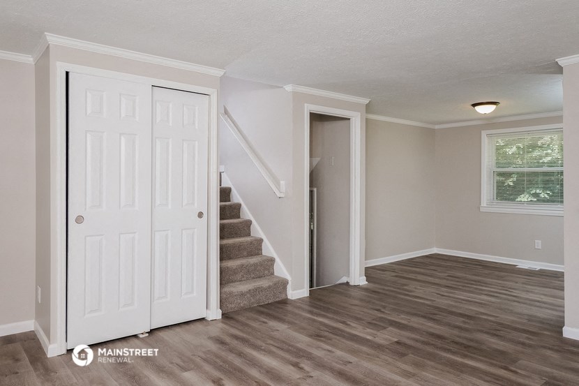 the living room of a renovated house with stairs and a white door