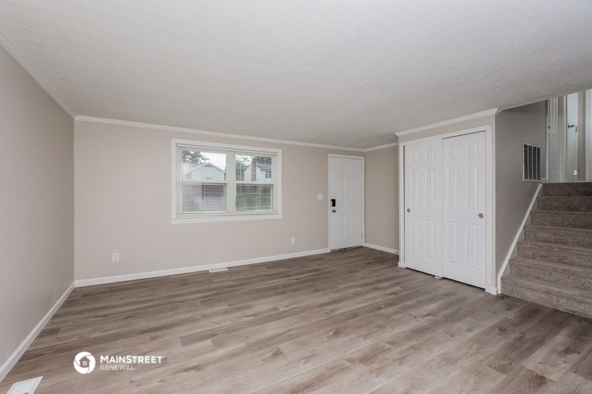 the living room of a house with a hardwood floor and a staircase