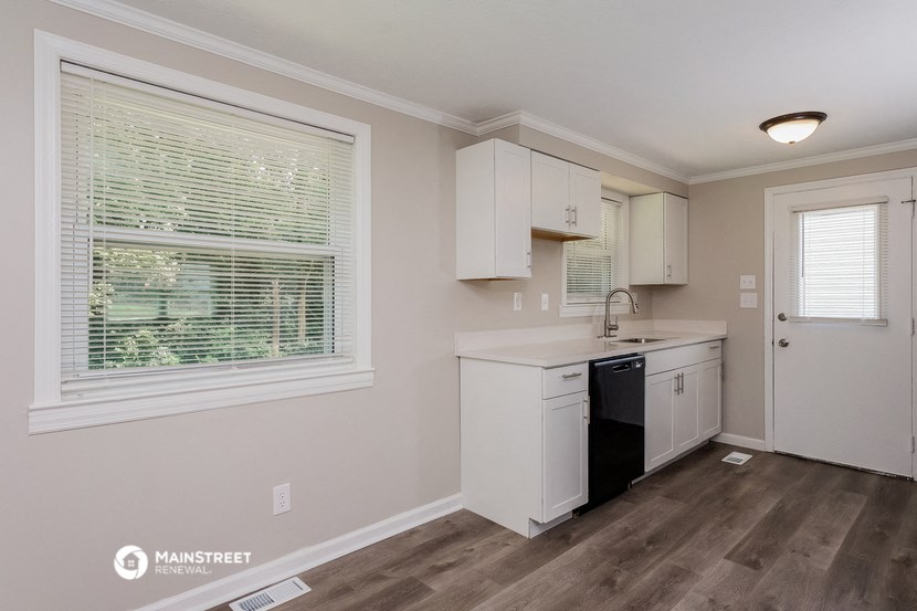 a small kitchen with white cabinets and a window