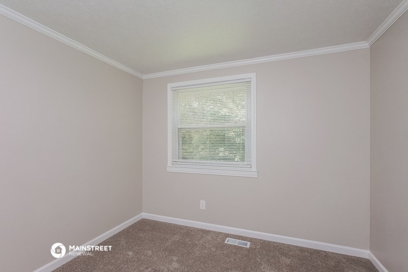 the bedroom of a house with a window and carpet