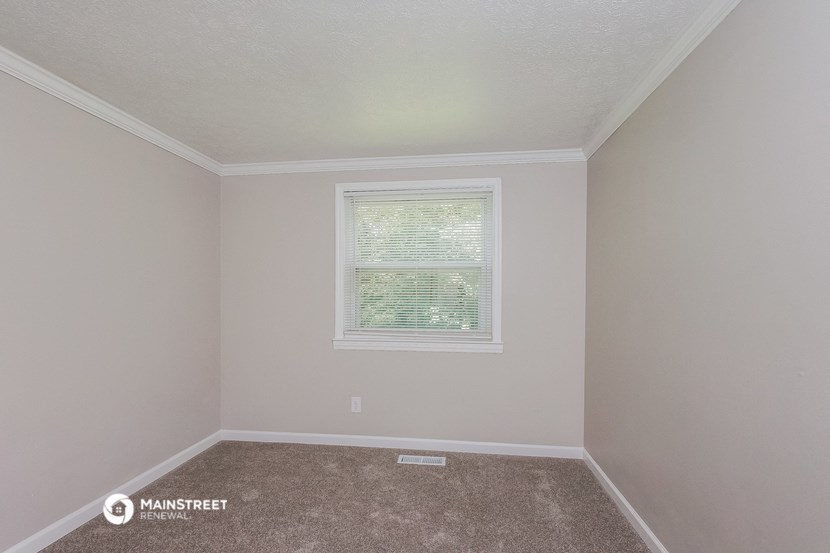 the bedroom of a rental home with carpet and a window