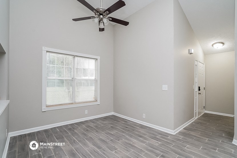 an empty bedroom with a ceiling fan and a window