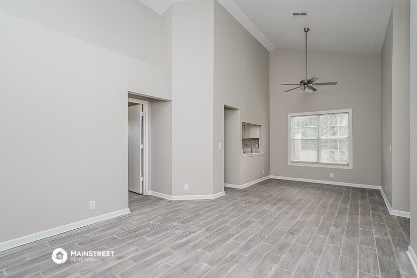an empty living room with a ceiling fan