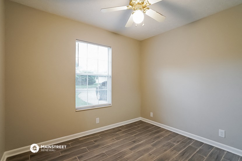 an empty room with a ceiling fan and a window