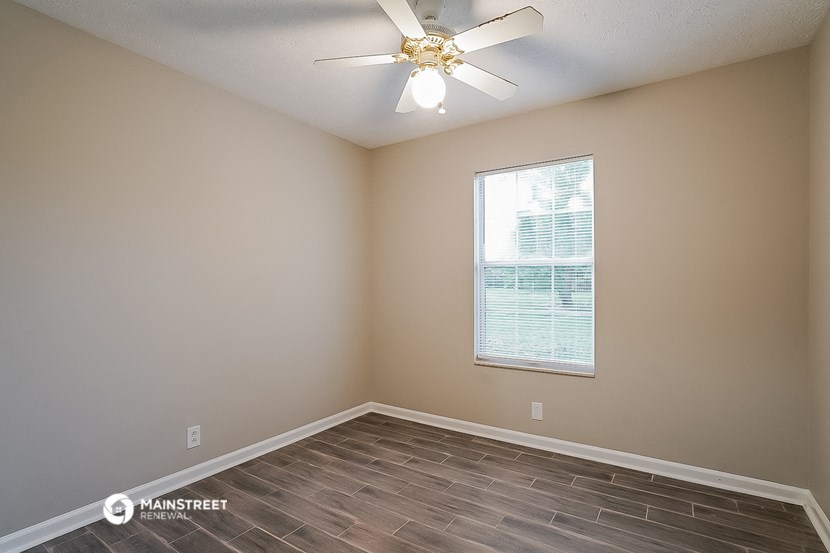 an empty room with a ceiling fan and a window