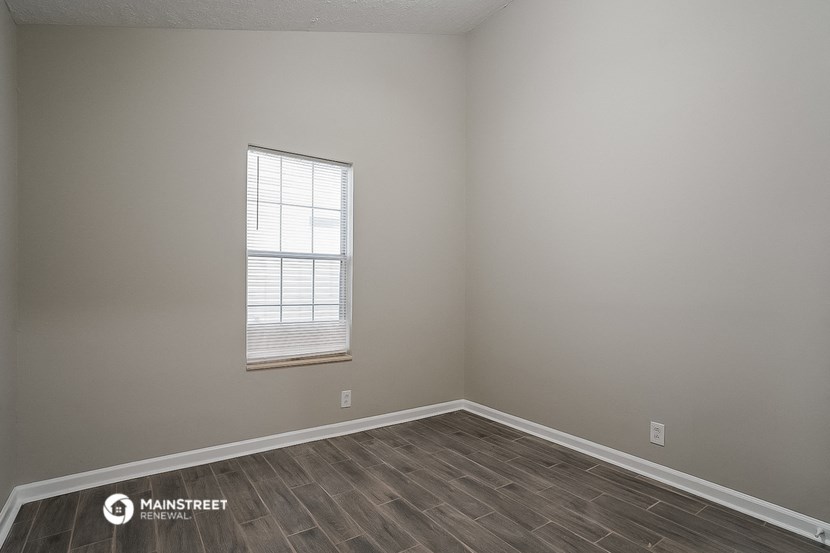 an empty room with a window and wooden floors