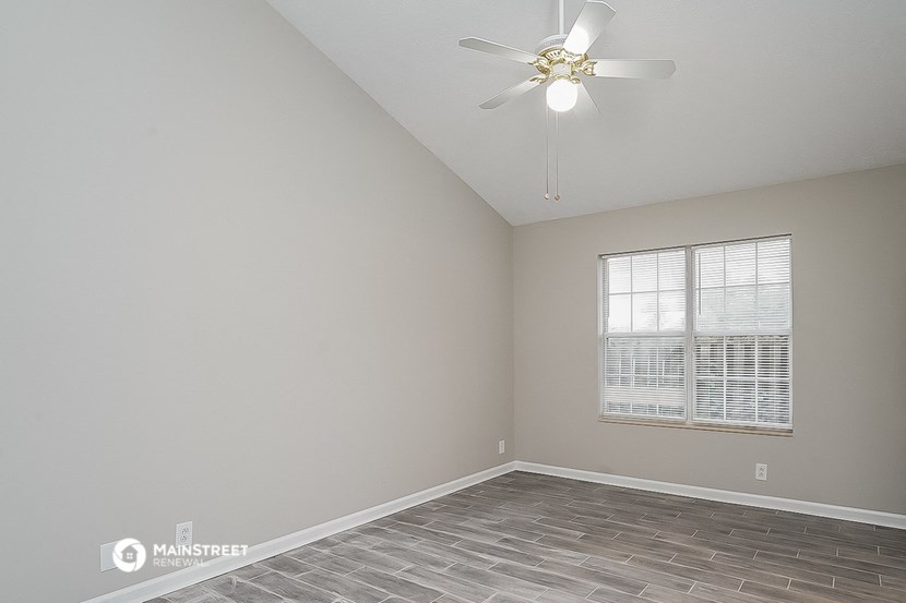 an empty bedroom with a ceiling fan and a window