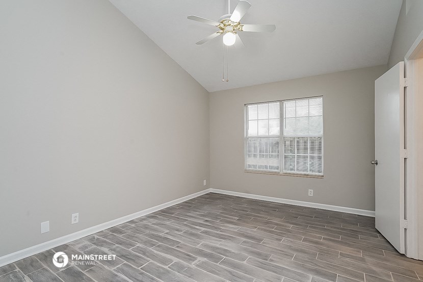 an empty room with a ceiling fan and a window