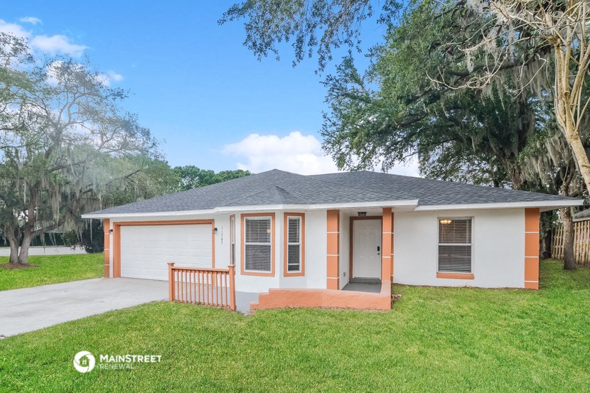 a small white house with a porch and a tree