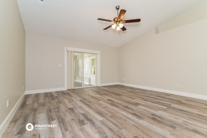 the spacious living room with hardwood floors and a ceiling fan