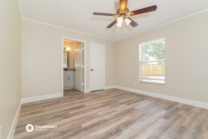 the living room of a home with a ceiling fan and a door to a bathroom