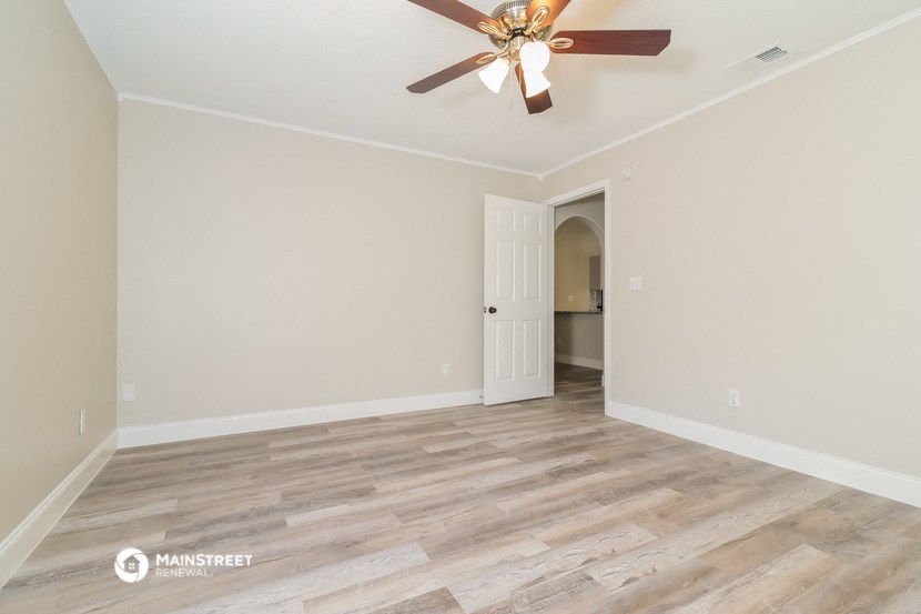 the spacious living room with wood flooring and a ceiling fan