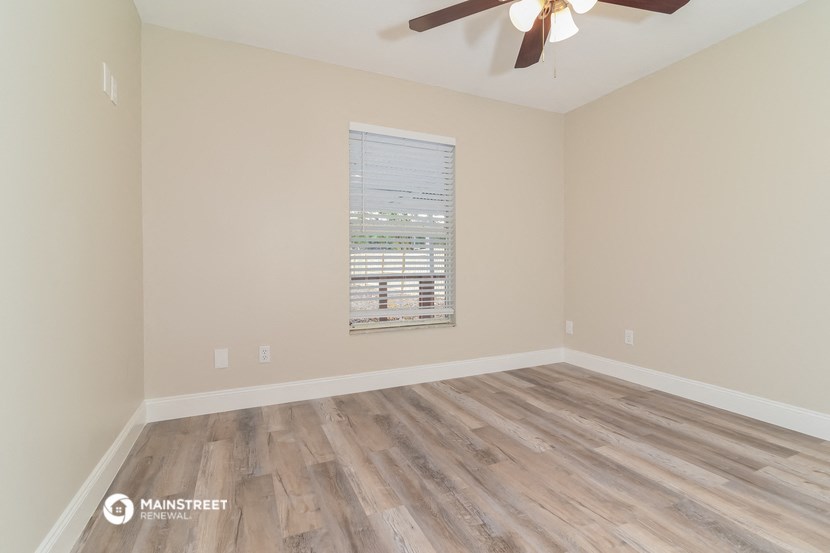 the spacious living room with hardwood floors and a ceiling fan
