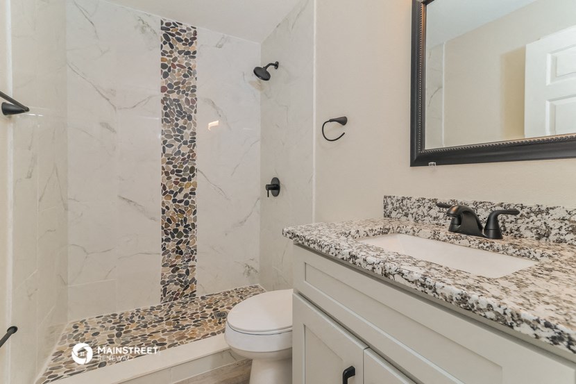 a bathroom with marble counter tops and a shower and sink