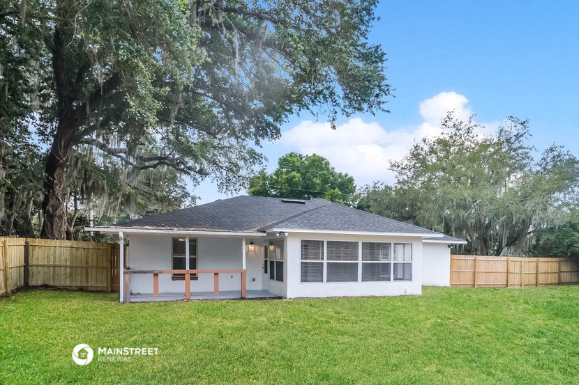 a small white house with a yard and a tree