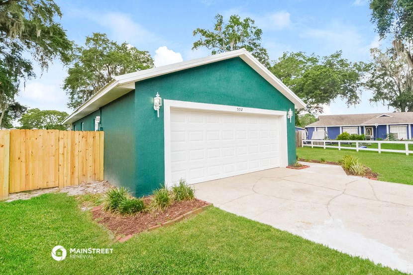 a green house with a white garage door