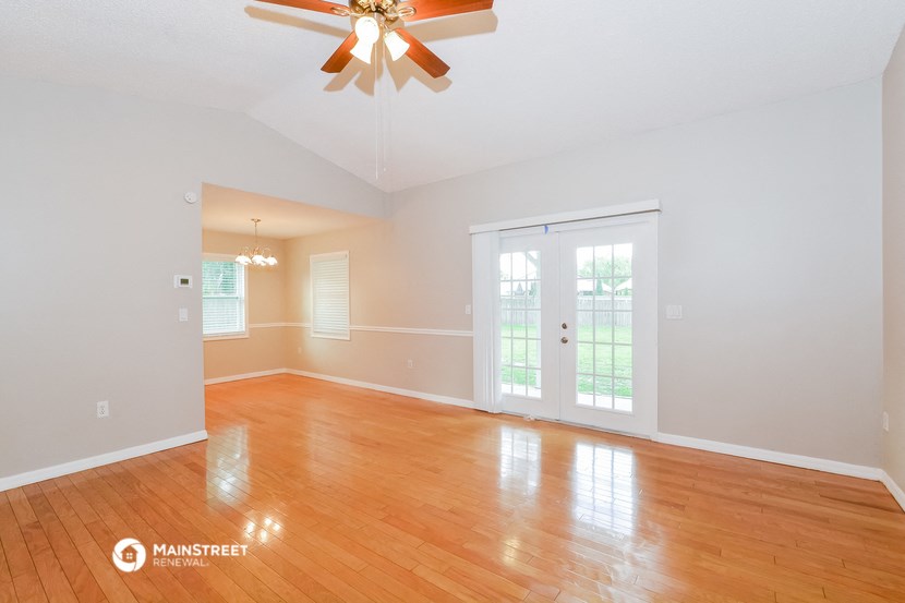 the living room with wood floors and a ceiling fan