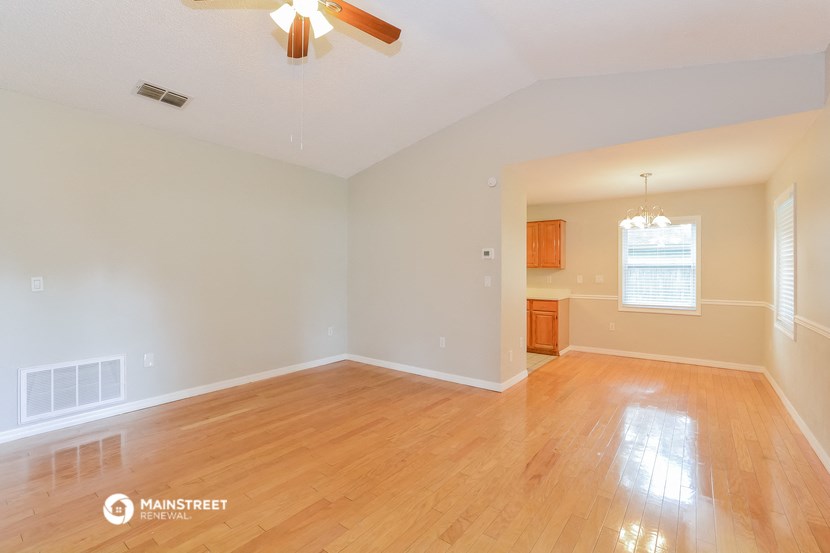 an empty living room with wood floors and a ceiling fan