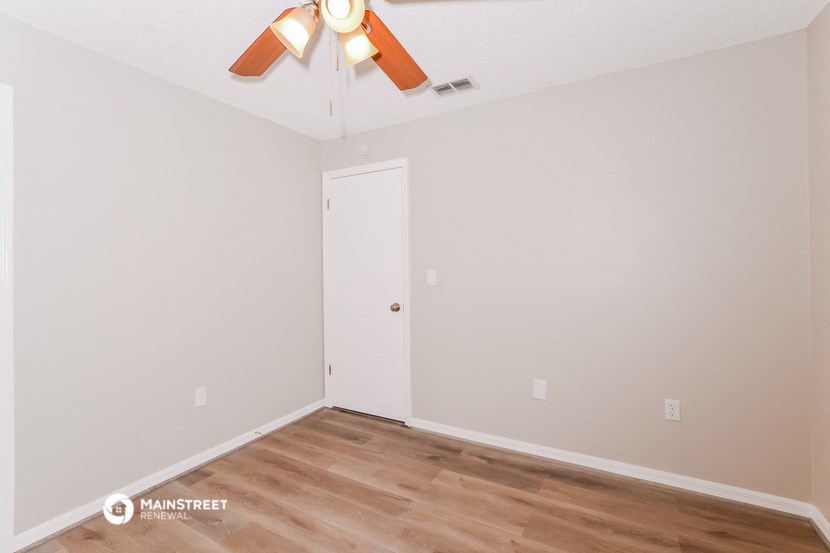 a bedroom with a ceiling fan and wood flooring
