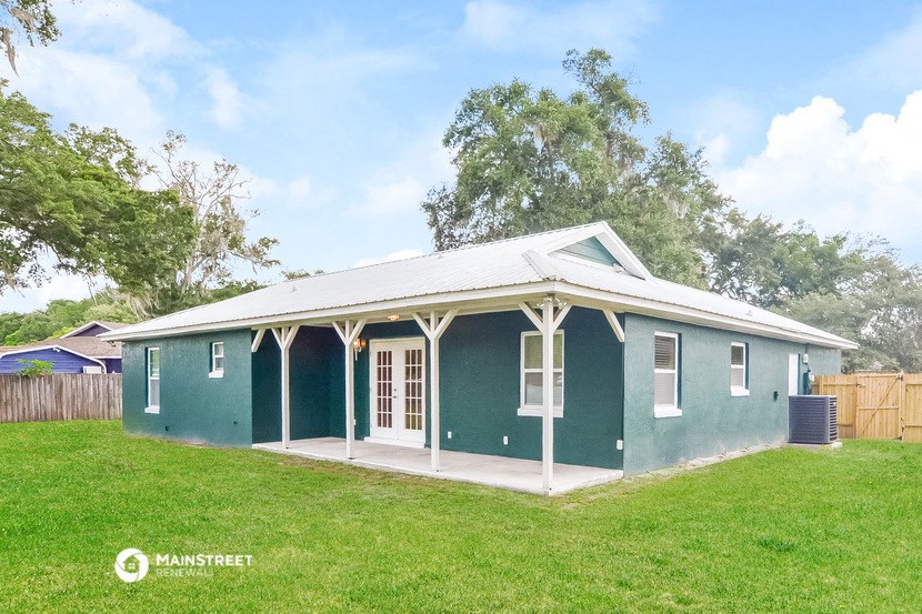 the exterior of a green house with a porch and a lawn