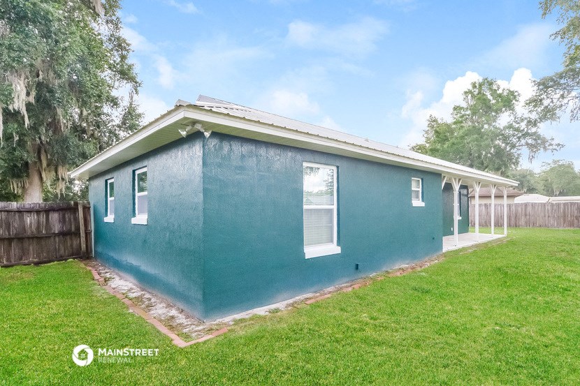 the exterior of a blue house with a lawn and a fence