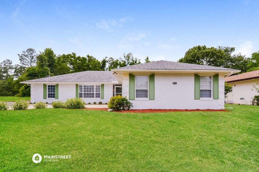 a small white house with green shutters and a green lawn