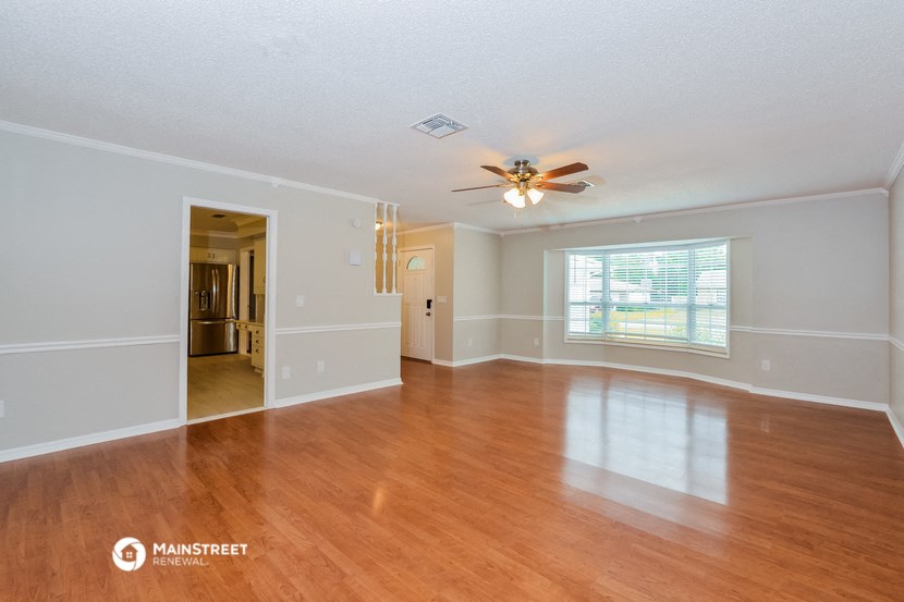 an empty living room with a ceiling fan and a window